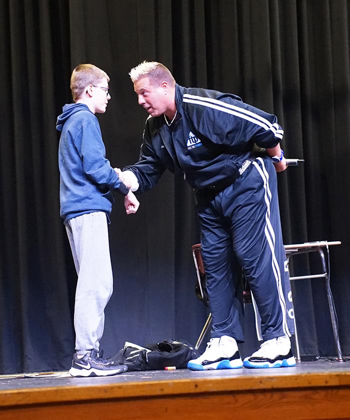 A man and a student stand onstage